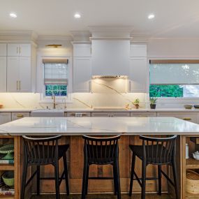 Floor to ceiling white cabinets are stunning against contrasting stained maple island
