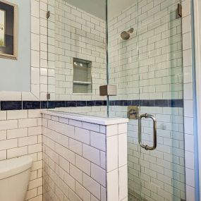 Decorative tile, a knee wall, and a frameless glass shower enclosure create a brighter, inviting shower in Wilmington.