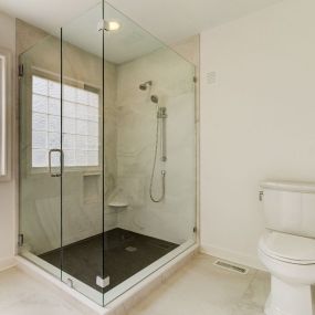 Full height glass enclosure around a large tile shower in Carolina Beach.