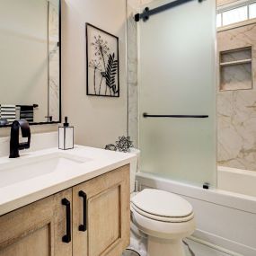 A floating vanity and a frosted glass barn door shower dress up a small bathroom in Leland.