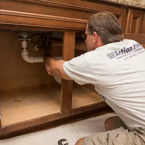 OBX plumber doing a faucet repair under a sink.