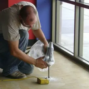 URETEK technician filling void under concrete slab by injecting URETEK foam